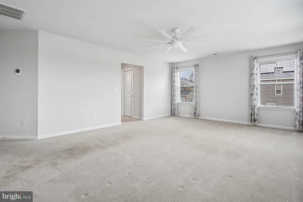 an empty room with a fan & a window