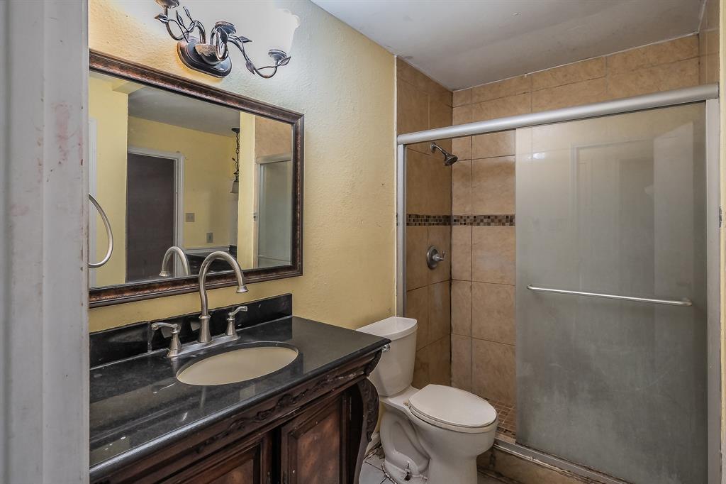 5709 Ranchogrande Drive Arlington, TX 76017 - Photo 18 of 28 a bathroom with a granite countertop sink toilet a mirror and shower