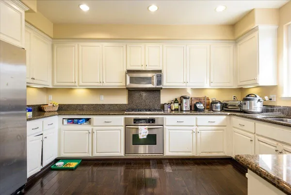 a kitchen with stainless steel appliances granite countertop a stove a sink and a white cabinets