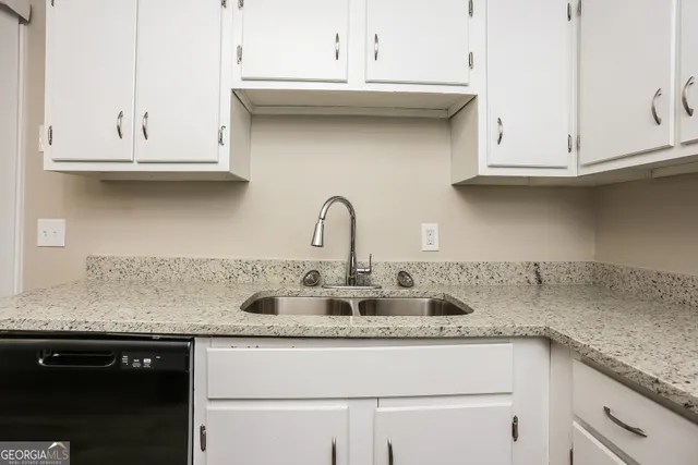 a kitchen with granite countertop white cabinets and a sink