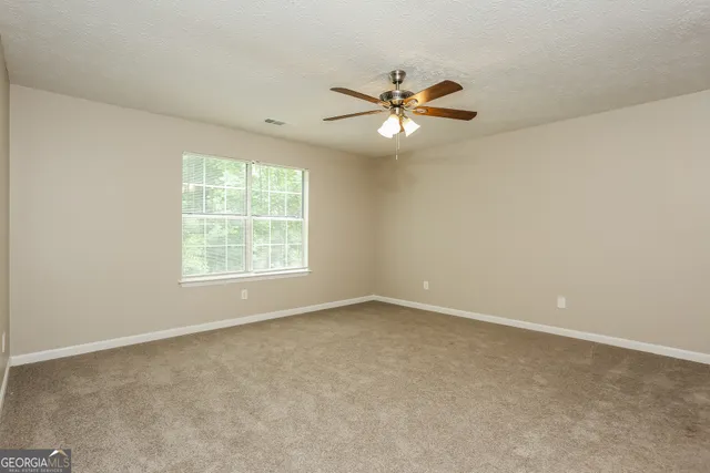 an empty room with a window and a fan