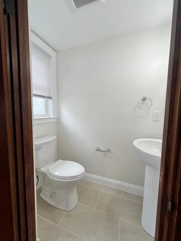 96 Brooks Street, Unit 1 Boston, MA 02135 - Photo 15 of 15 a white toilet sitting next to a bathroom sink and vanity