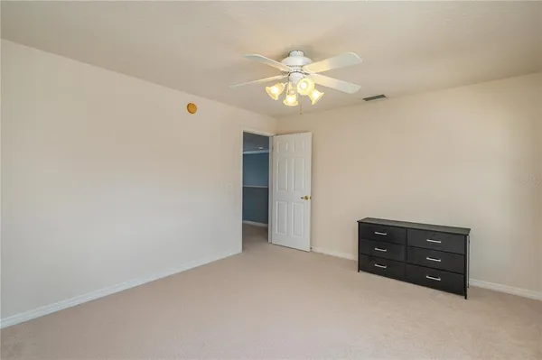 a view of an empty room with chandelier fan
