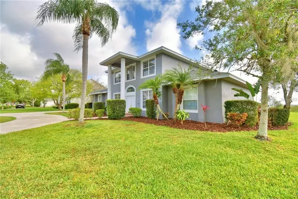 a front view of a house with a yard and palm trees