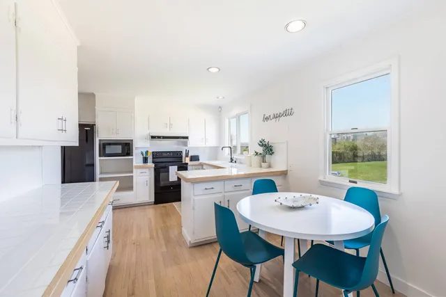 a kitchen with stainless steel appliances kitchen island granite countertop a dining table chairs and granite counter tops