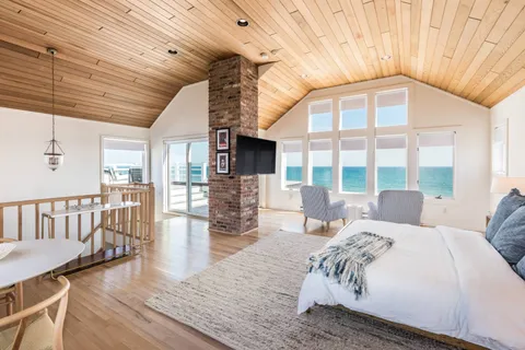 a bedroom with a bed a table and wooden floor