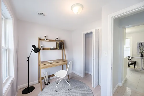 a view of a hallway with chairs and a wooden floor