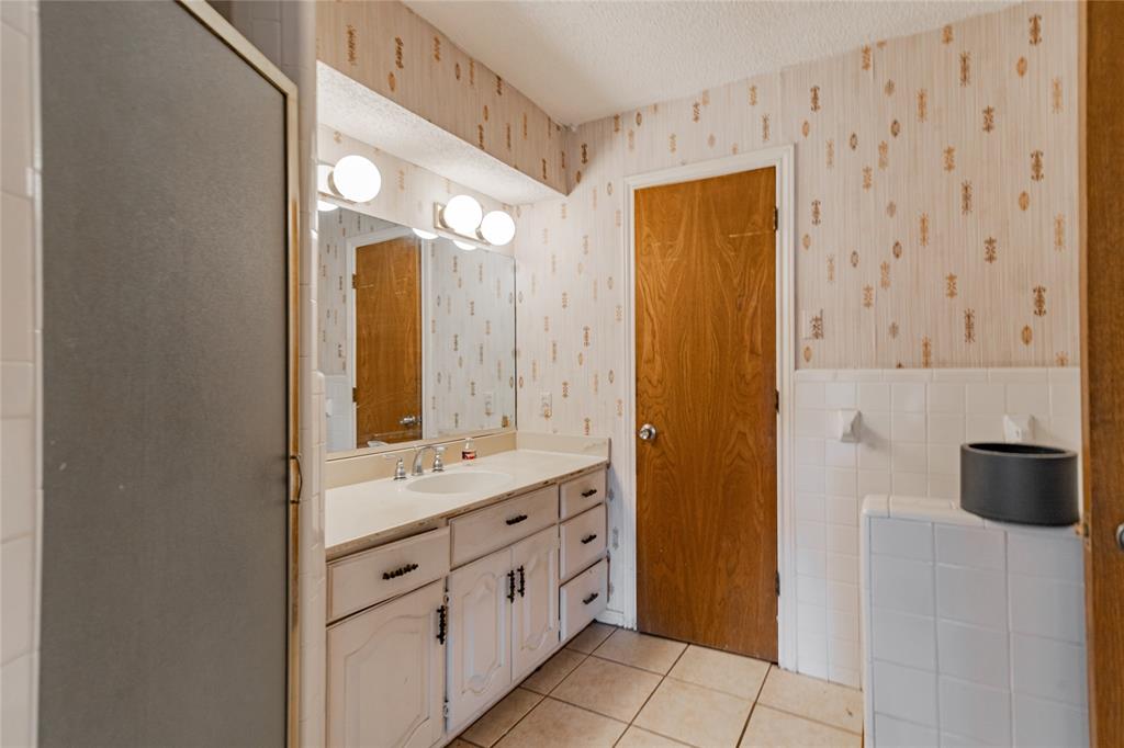 4320 Hickox Road Rowlett, TX 75089 - Photo 35 of 37 Single vanity with a white countertop and integrated sink, dual-door white cabinetry, and a three-bulb vanity light fixture