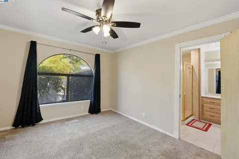 an empty room with chandelier fan and windows