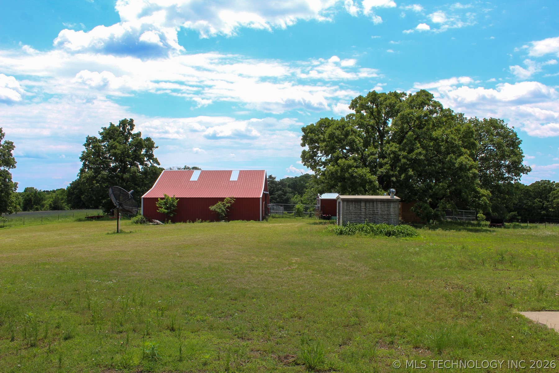 13248 North 3540th Road Maud, OK 74854 - Photo 82 of 98 Expansive green acreage featuring a red barn with a metal roof, mature trees, and a secondary outbuilding
