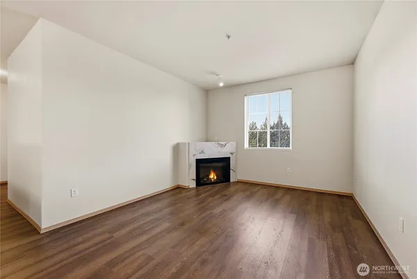 an empty room with wooden floor fireplace and windows