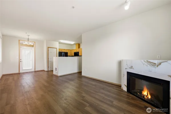 a view of an empty room with wooden floor and fire place
