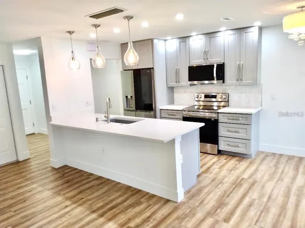 a kitchen with kitchen island granite countertop a sink appliances and cabinets