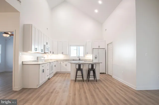 a kitchen with kitchen island granite countertop white cabinets and refrigerator
