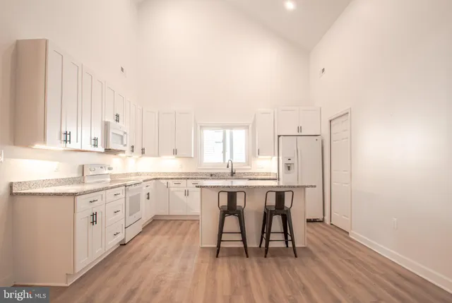 a kitchen with granite countertop white cabinets white appliances and sink