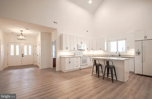 a view of an empty room with wooden floor fireplace and a window