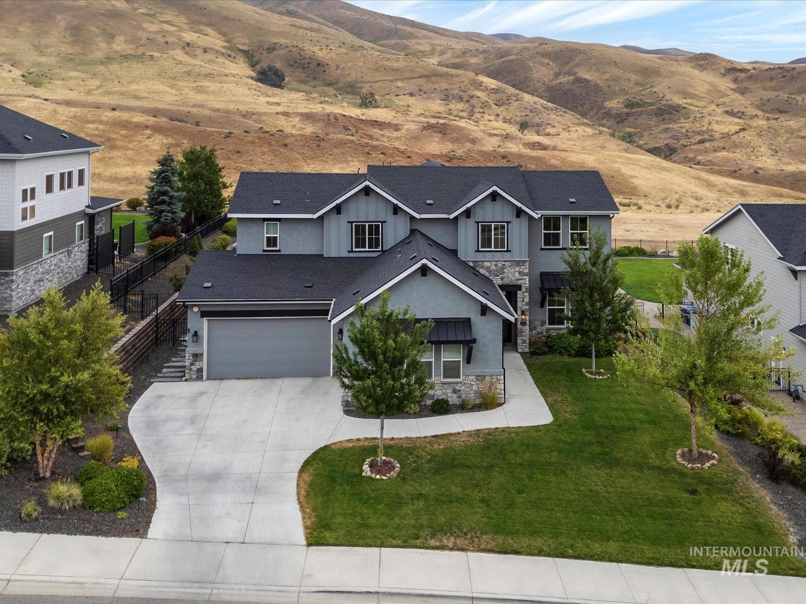 View of front of house with stone siding, a mountain view, driveway, and a garage