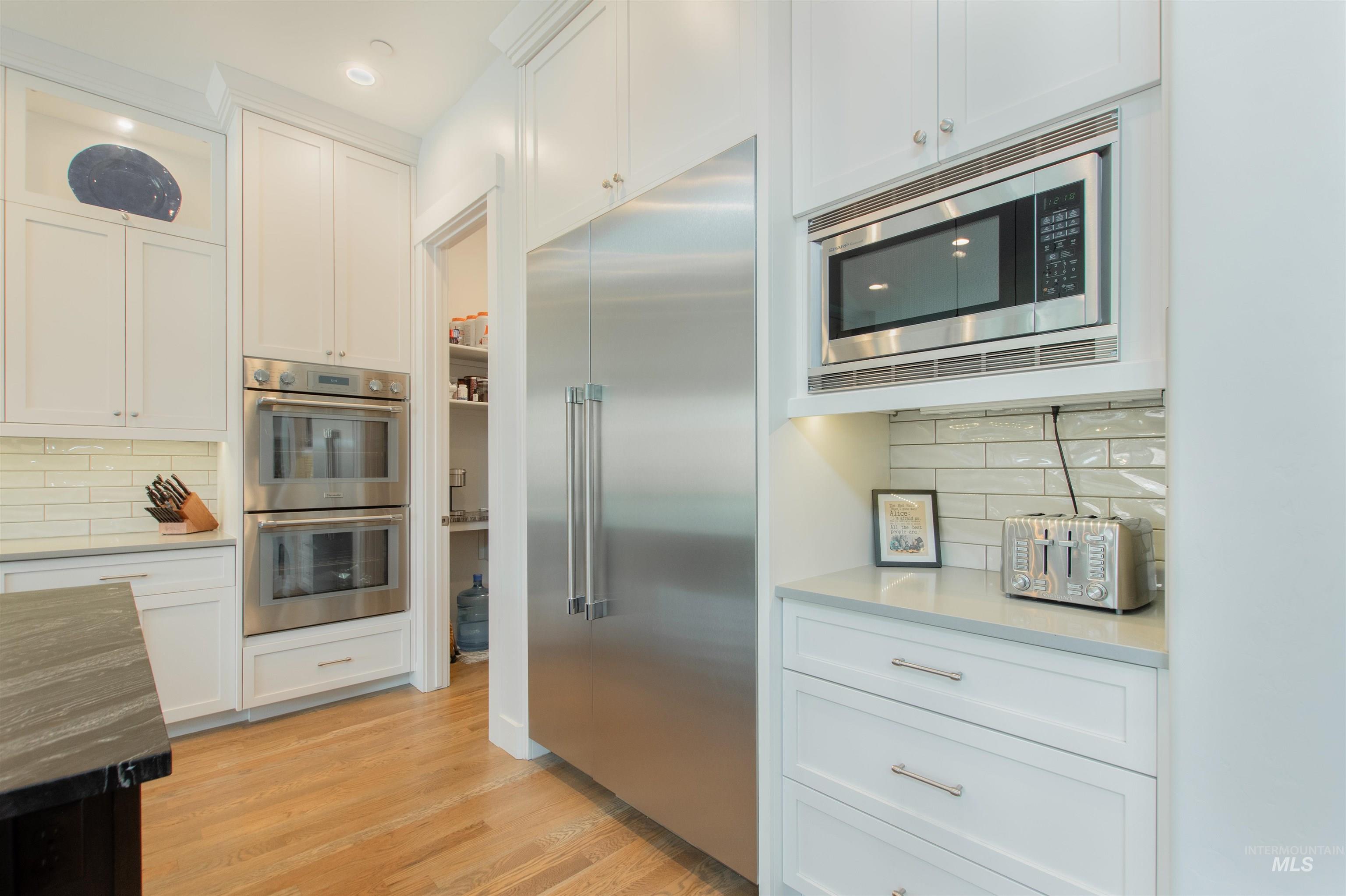 2400 South Trapper Place Boise, ID 83716 - Photo 11 of 50 Kitchen featuring decorative backsplash, built in appliances, white cabinetry, dark stone counters, and recessed lighting