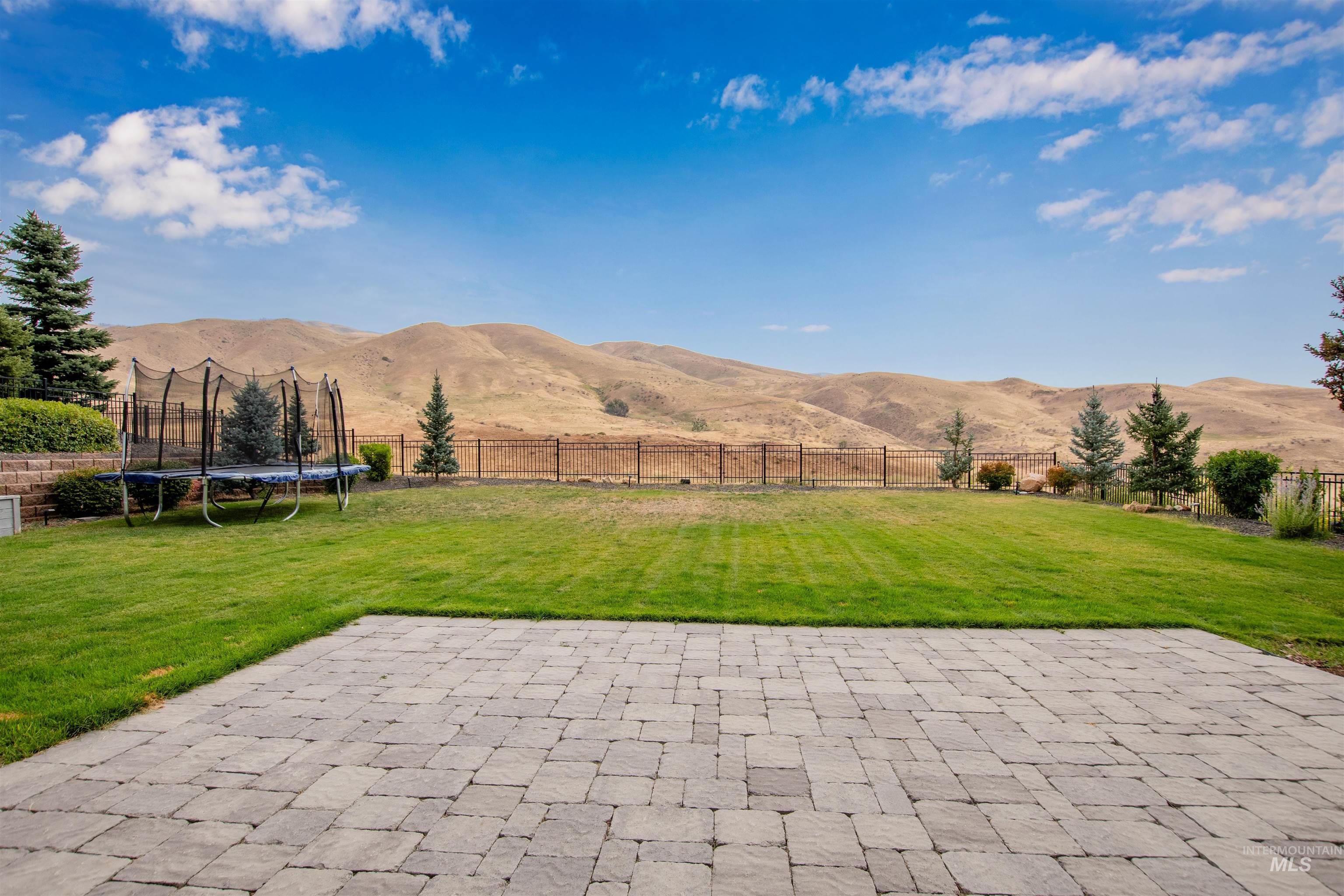 2400 South Trapper Place Boise, ID 83716 - Photo 38 of 50 Fenced backyard with a mountain view, a patio, a trampoline, and a view of rural / pastoral area