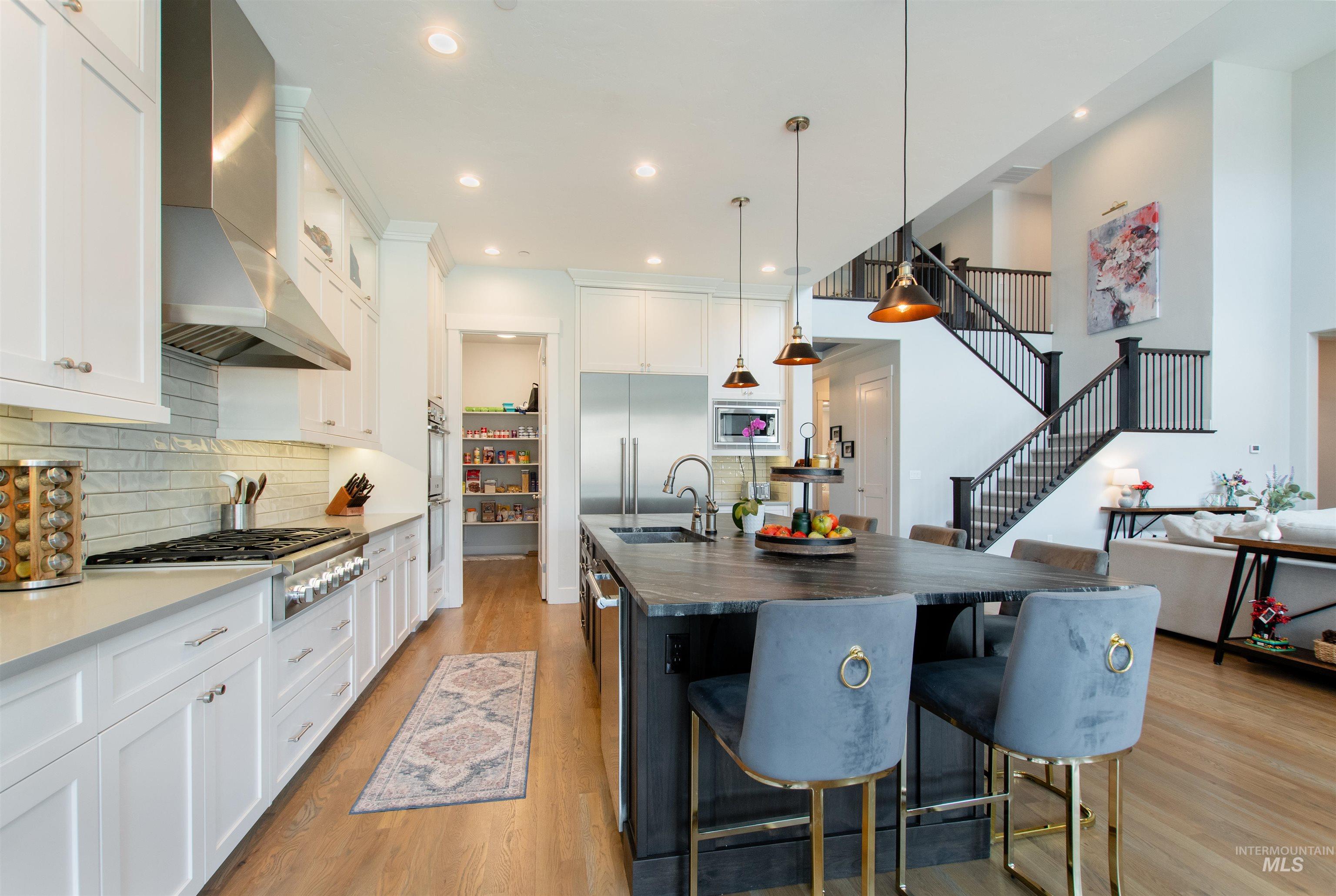 2400 South Trapper Place Boise, ID 83716 - Photo 10 of 50 Kitchen featuring tasteful backsplash, a breakfast bar area, a center island with sink, pendant lighting, and light wood-type flooring