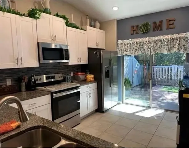 a kitchen with stainless steel appliances a stove a sink a microwave a refrigerator and cabinets