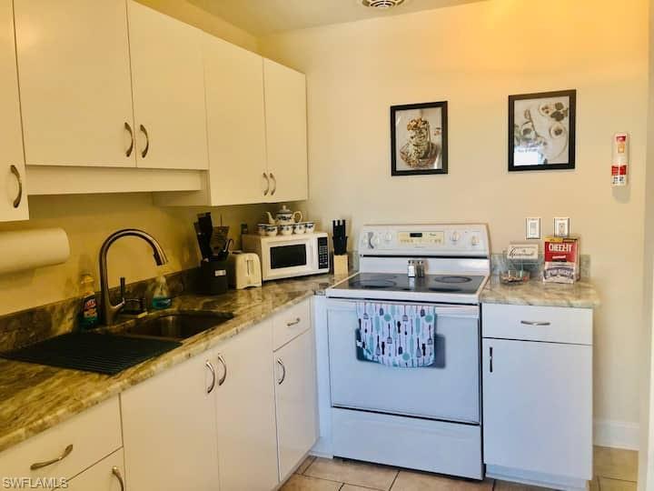 1726 Bikini Court, Unit R Cape Coral, FL 33904 - Photo 6 of 14 a kitchen with stainless steel appliances granite countertop a stove a sink and a white refrigerator with white cabinets