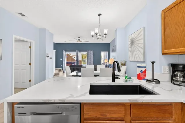 a kitchen with a sink dishwasher a stove and a dining table with wooden floor