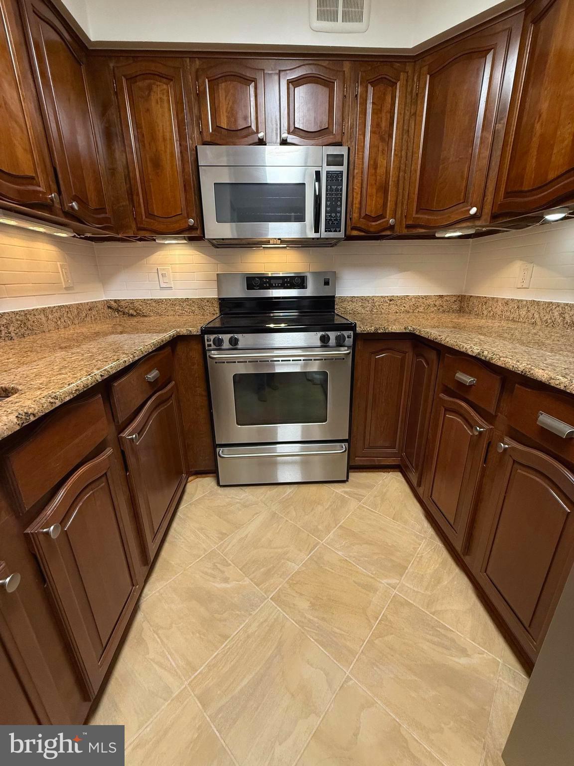 1077 30th Street Northwest, Unit 612 Washington, DC 20007 - Photo 14 of 44 a kitchen with stainless steel appliances granite countertop a stove a sink and a microwave
