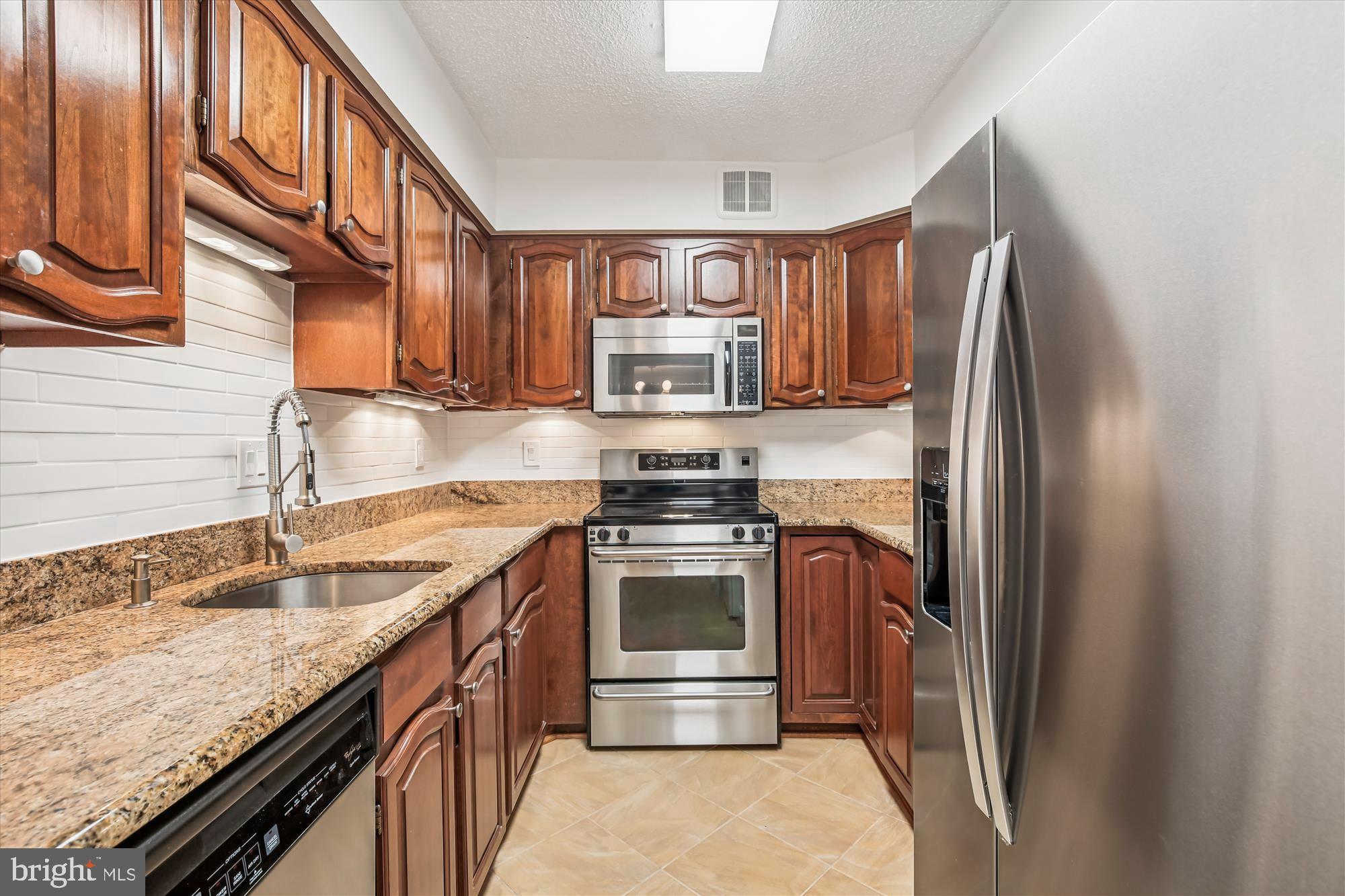 1077 30th Street Northwest, Unit 612 Washington, DC 20007 - Photo 16 of 44 a kitchen with granite countertop a refrigerator stove and oven