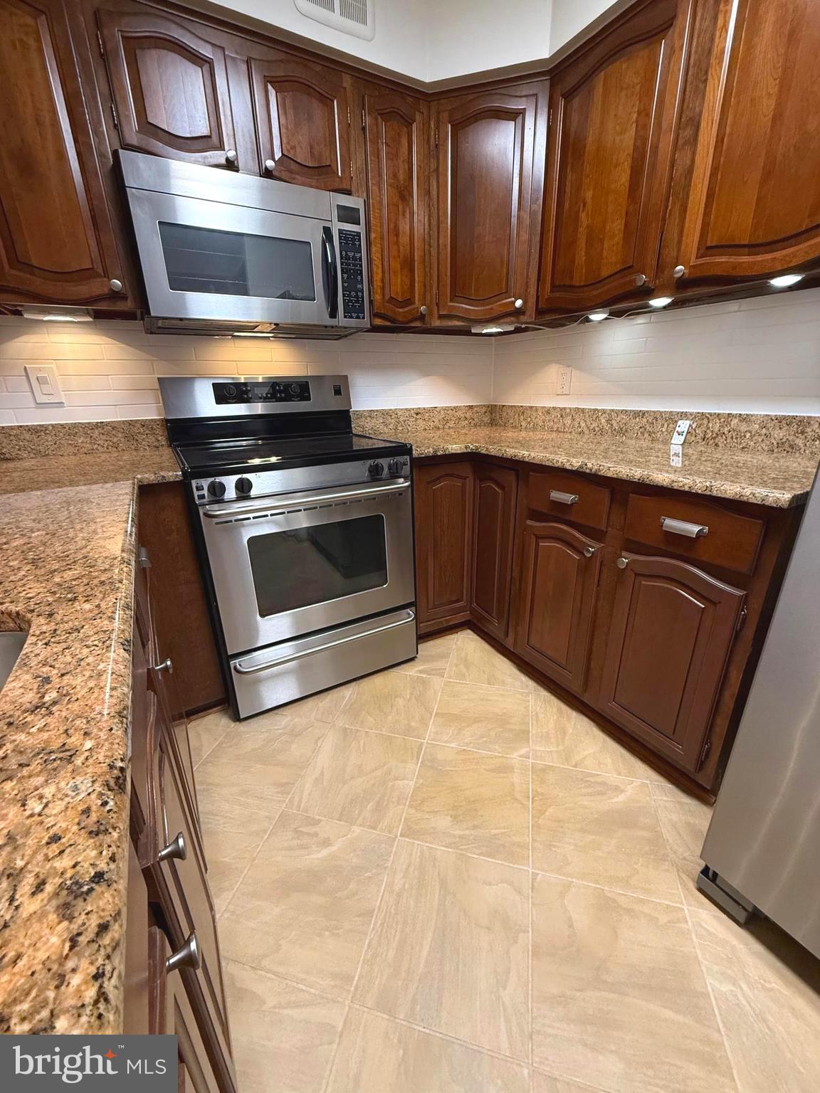 1077 30th Street Northwest, Unit 612 Washington, DC 20007 - Photo 17 of 44 a kitchen with stainless steel appliances granite countertop a stove a sink and a microwave