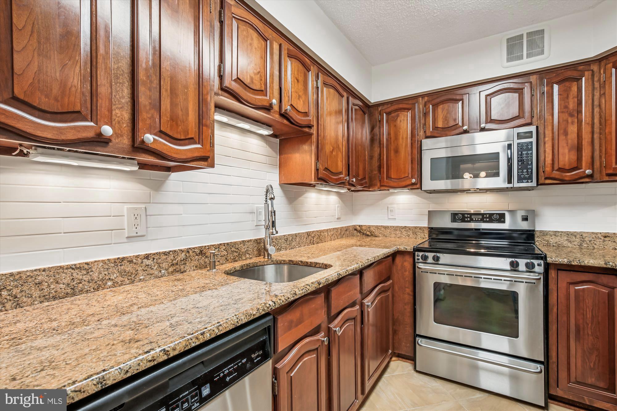 1077 30th Street Northwest, Unit 612 Washington, DC 20007 - Photo 18 of 44 a kitchen with granite countertop a sink a stove and cabinets