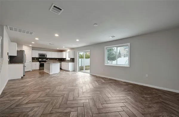a view of kitchen with kitchen island a stove a refrigerator cabinets and living room view