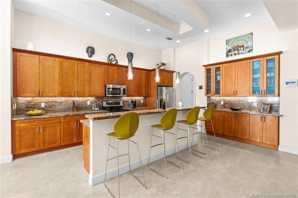 4940 Southeast Inlet Isle Way Stuart, FL 34997 - Photo 16 of 75 a kitchen with stainless steel appliances granite countertop a stove sink and cabinets