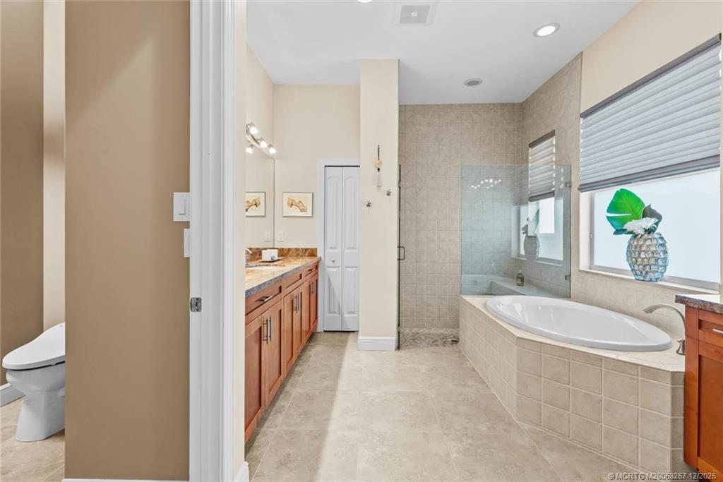 4940 Southeast Inlet Isle Way Stuart, FL 34997 - Photo 32 of 75 a spacious bathroom with a granite countertop tub sink a mirror a shower and a toilet