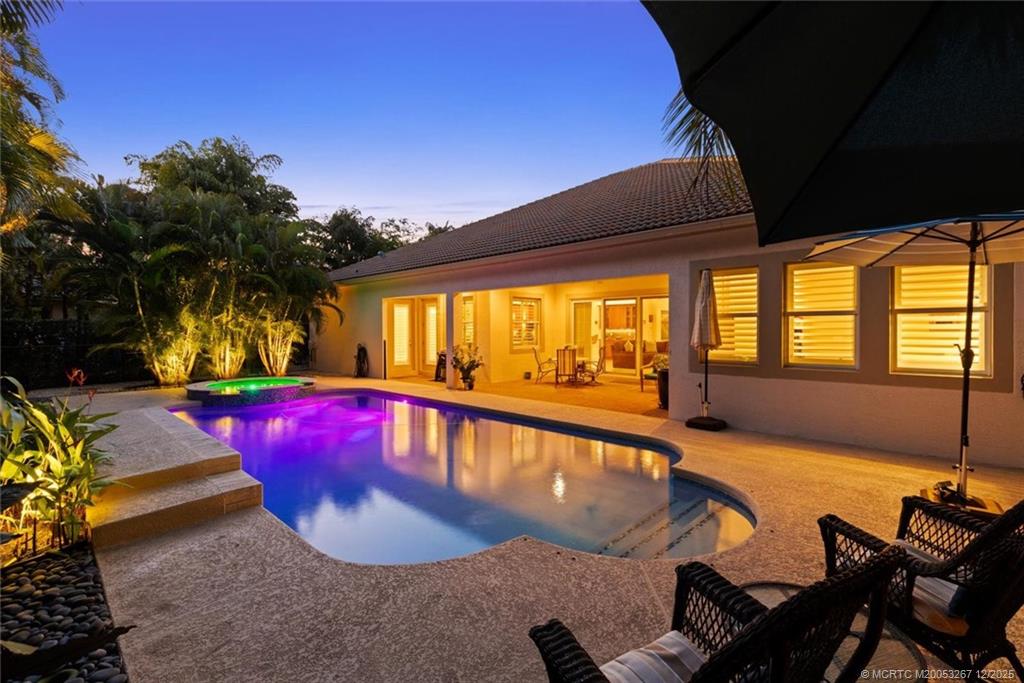 4940 Southeast Inlet Isle Way Stuart, FL 34997 - Photo 52 of 75 a view of a swimming pool with red chairs in front of house