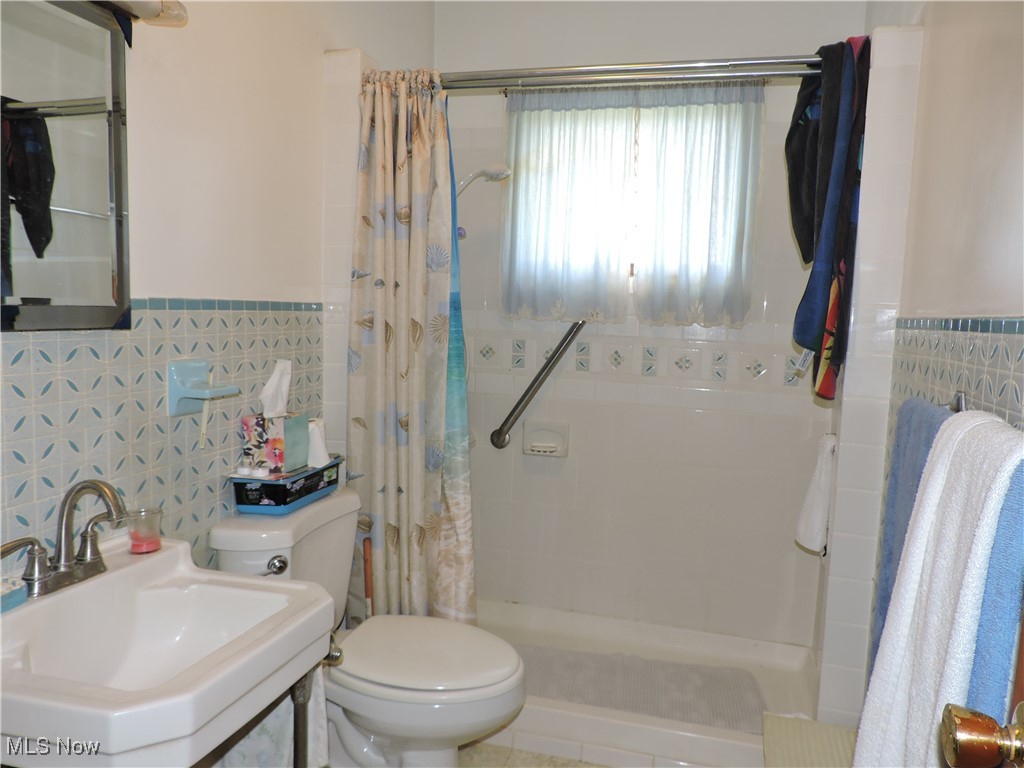 39115 Parsons Road Grafton, OH 44044 - Photo 6 of 9 Bathroom with wainscoting, curtained shower, a sink, and tile walls