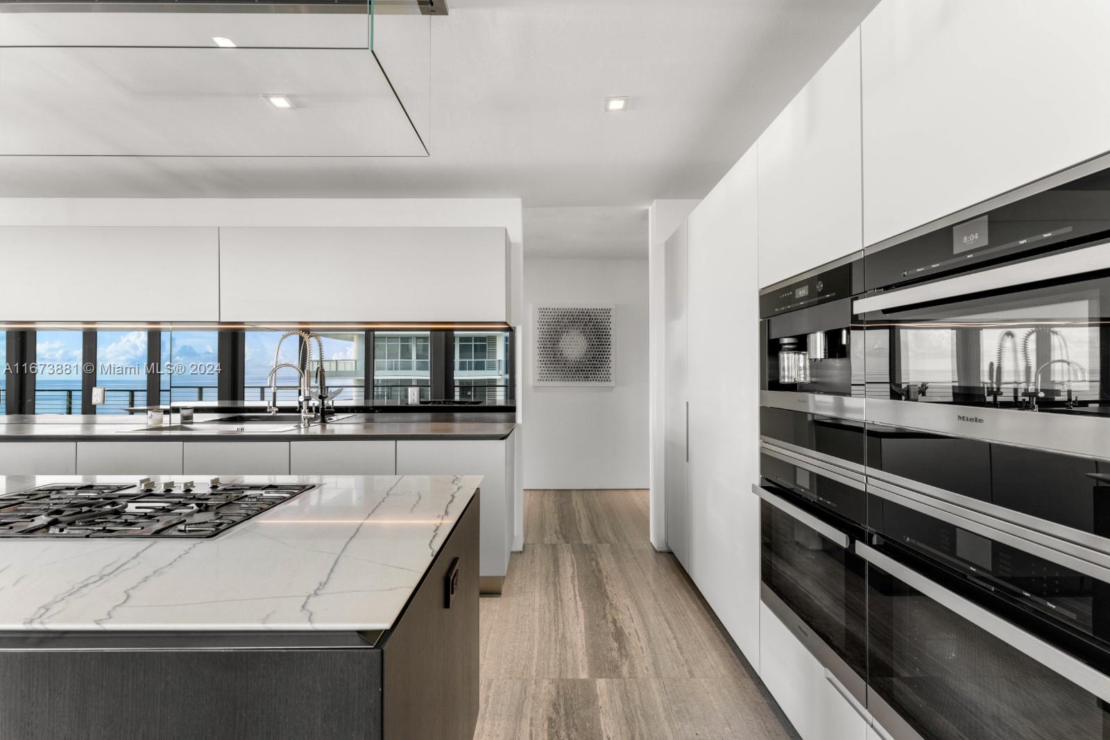 3651 Collins Avenue, Unit 800 Miami Beach, FL 33140 - Photo 16 of 33 a kitchen with a stove and white cabinets