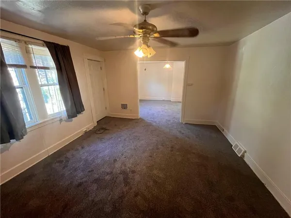an empty room with windows and fan