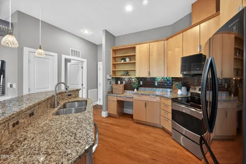 a large kitchen with stainless steel appliances granite countertop a stove refrigerator and a sink