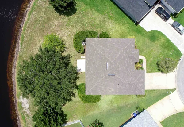 an aerial view of residential house with outdoor space and trees all around