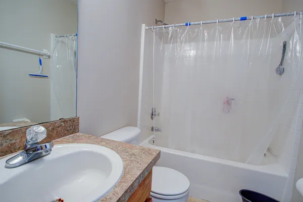 a bathroom with a granite countertop bathtub shower sink vanity and toilet