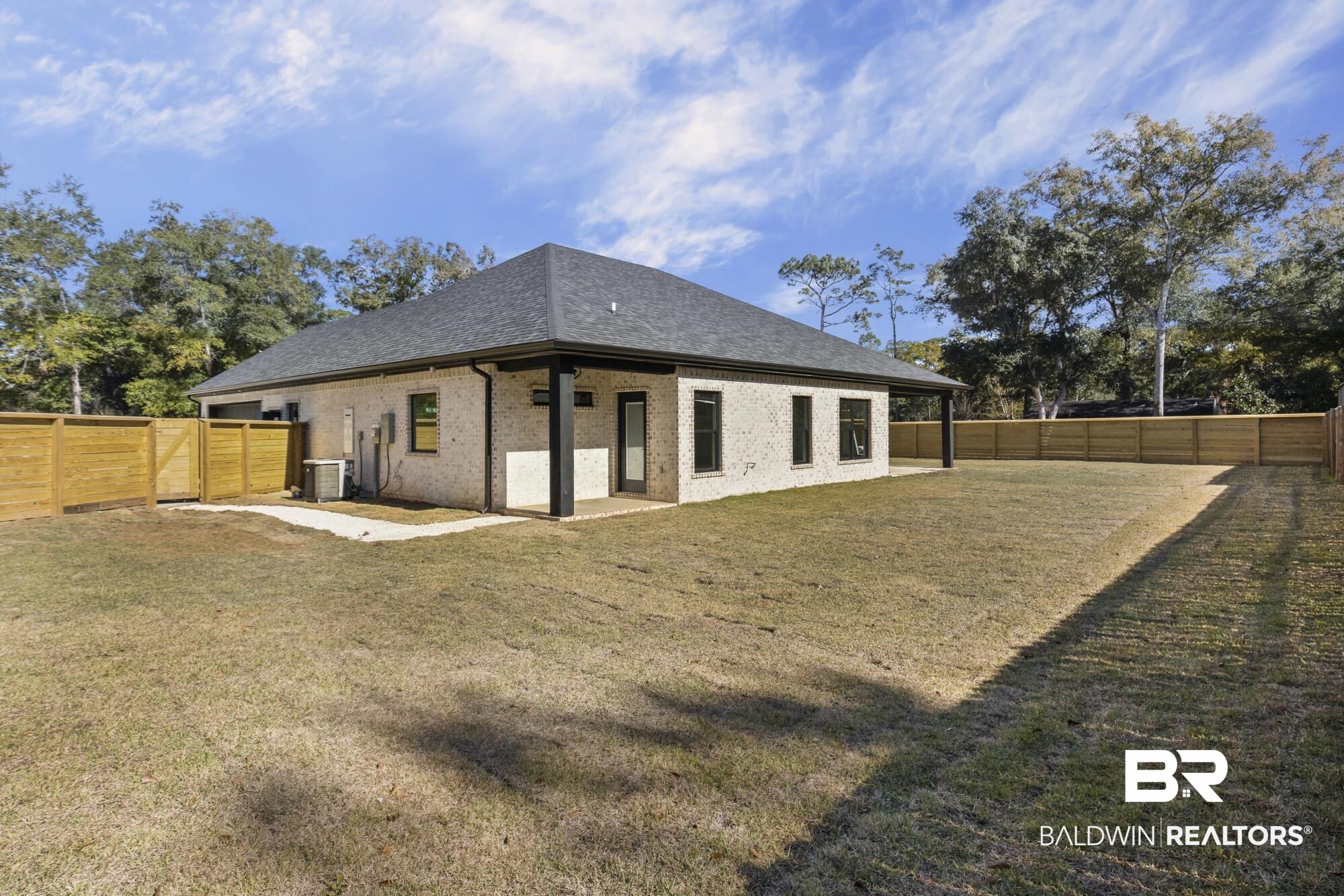 10180 Pineview Drive Foley, AL 36535 - Photo 32 of 47 Back of property with a fenced backyard, a patio area, brick siding, and a shingled roof
