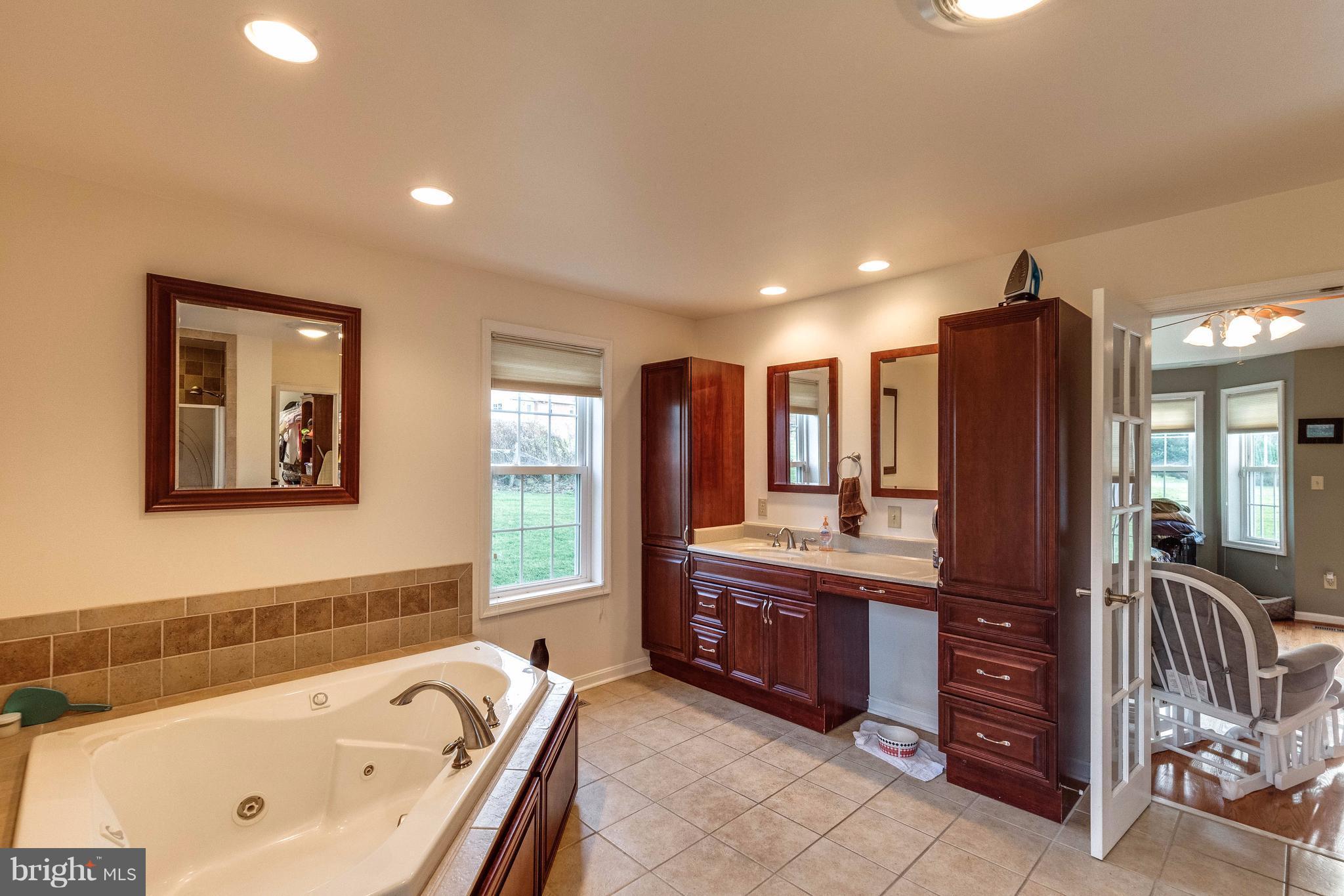 25453 Highfield Road Cascade, MD 21719 - Photo 18 of 30 a spacious bathroom with a tub a double vanity sink and a large mirror