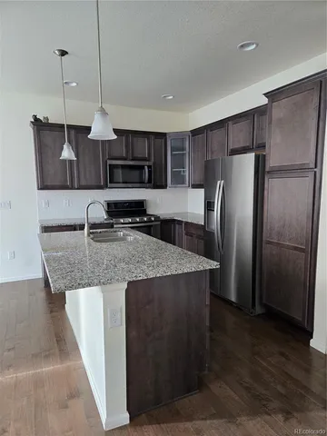 a kitchen with stainless steel appliances granite countertop a refrigerator a sink a stove and a wooden floors