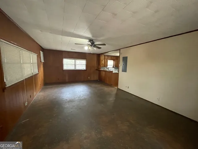 an empty room with windows and chandelier fan