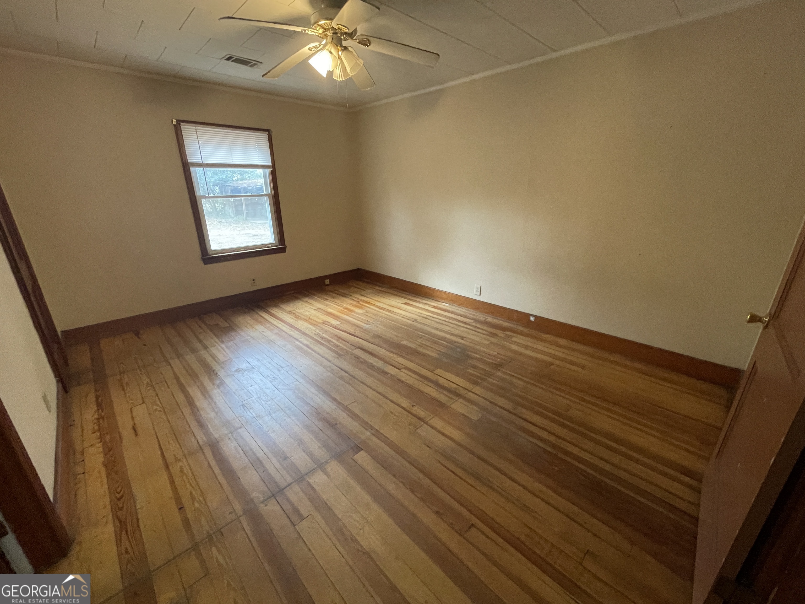 104 4th Street Cochran, GA 31014 - Photo 17 of 41 an empty room with wooden floor and windows