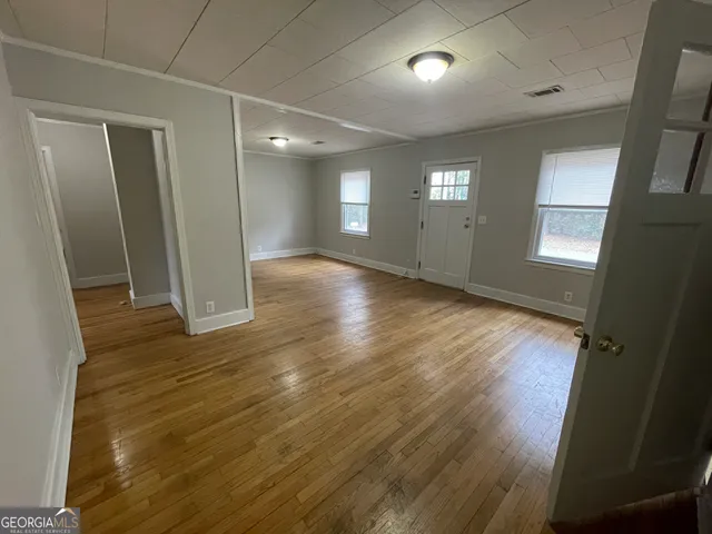 an empty room with wooden floor and windows