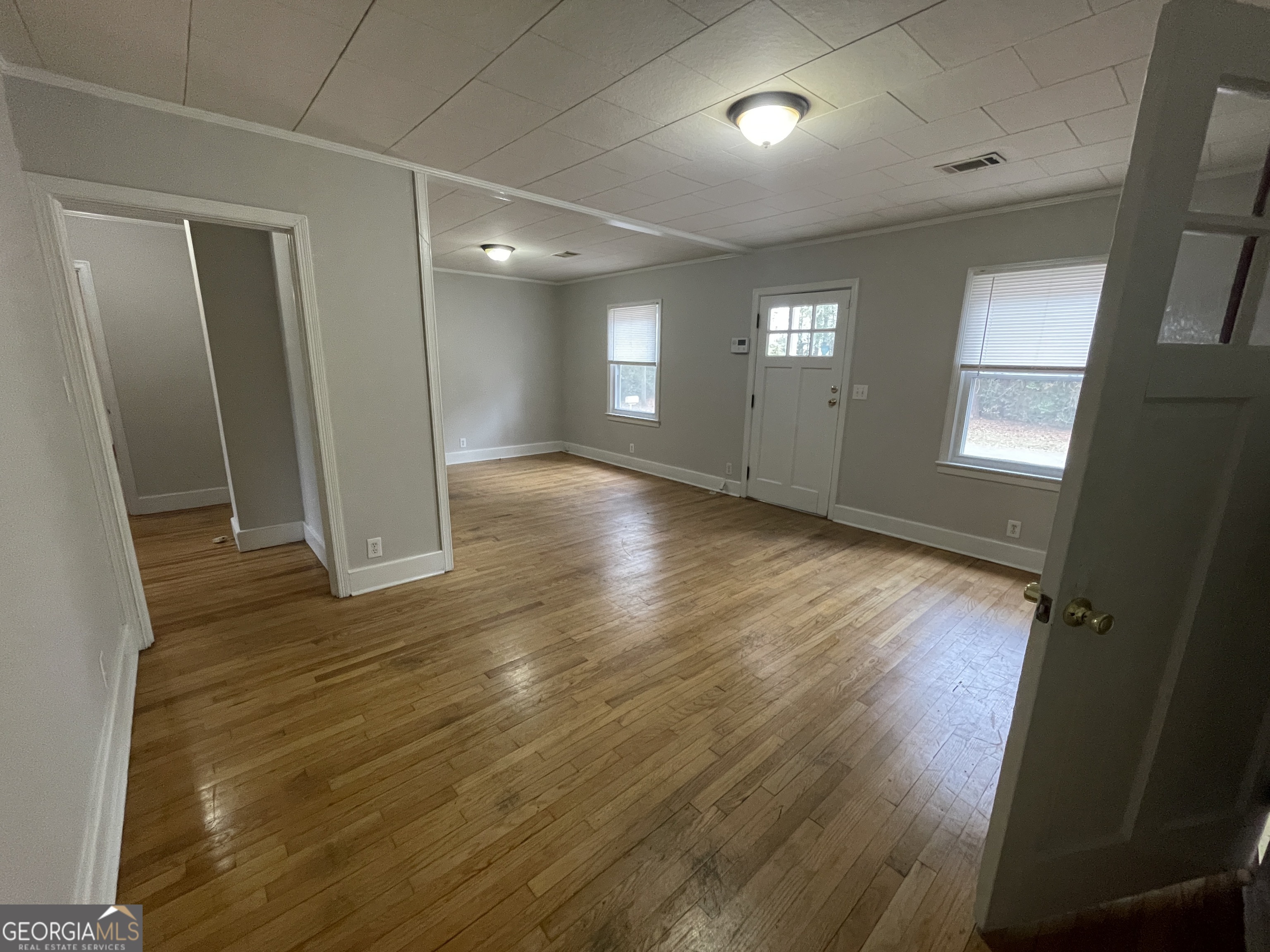104 4th Street Cochran, GA 31014 - Photo 8 of 41 an empty room with wooden floor and windows