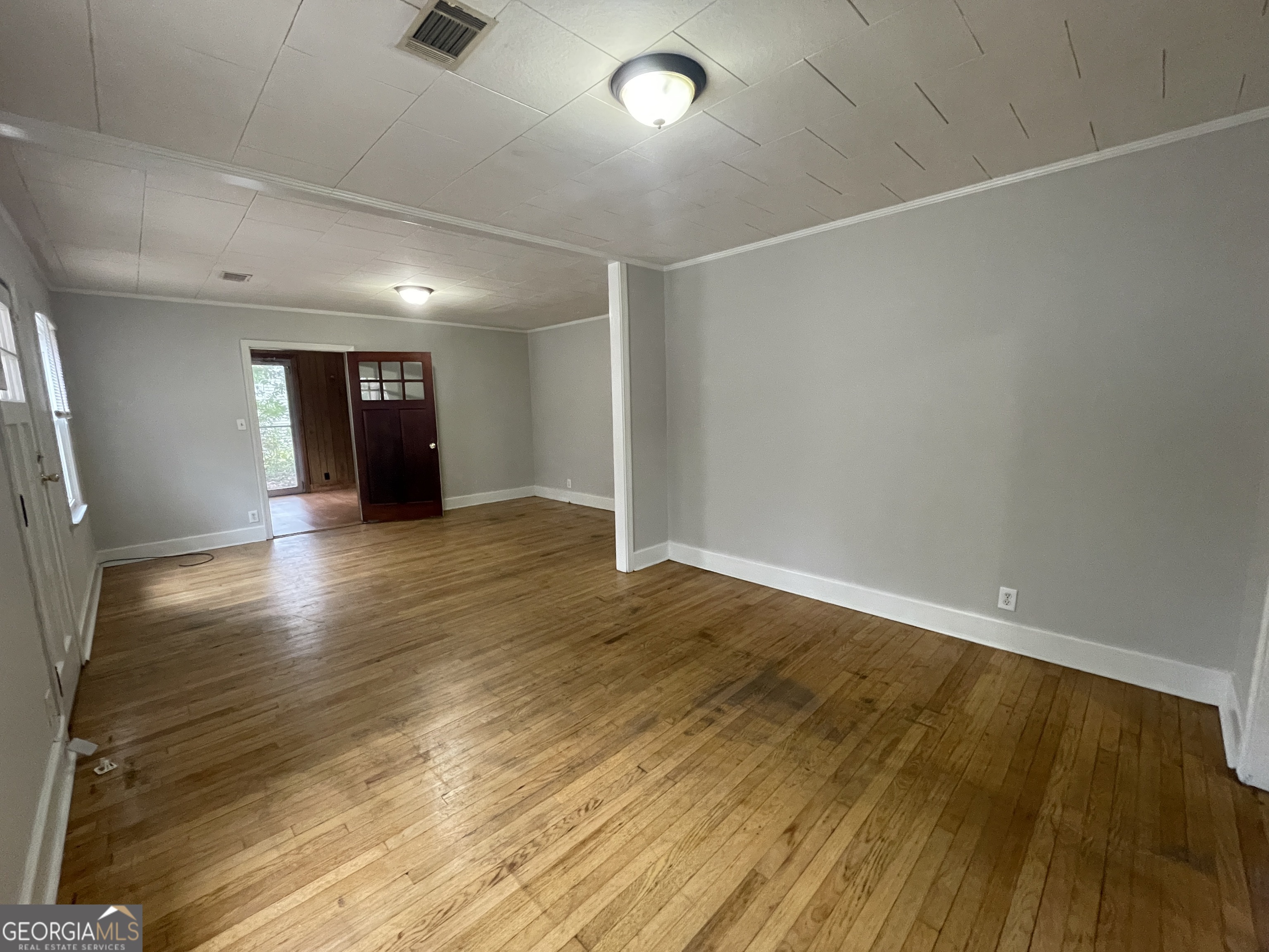 104 4th Street Cochran, GA 31014 - Photo 9 of 41 an empty room with wooden floor and windows