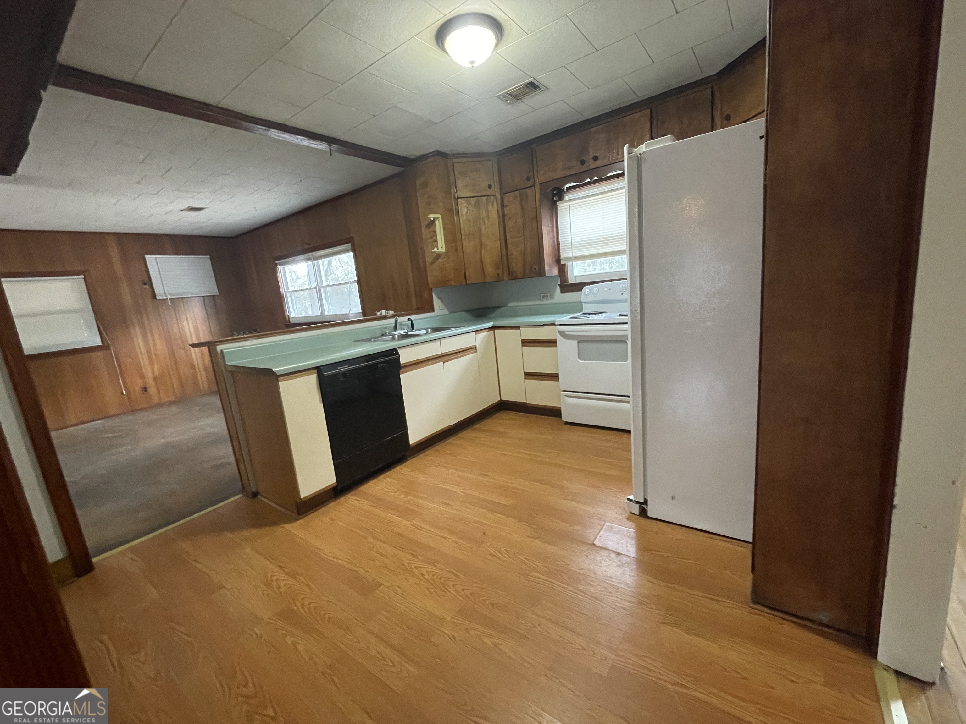 104 4th Street Cochran, GA 31014 - Photo 10 of 41 a large kitchen with a refrigerator a sink dishwasher a stove and white cabinets with wooden floor